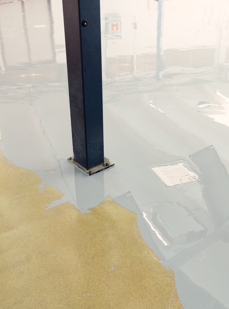 Worker applying epoxy resin to the floor of an industrial facility, creating a smooth and durable surface
